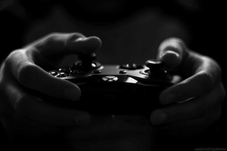 Close-up of hands holding a game controller in a monochrome setting, capturing the essence of gaming.